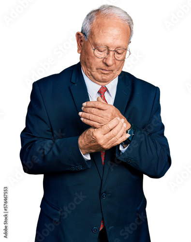 Senior man with grey hair wearing business suit and glasses suffering pain on hands and fingers, arthritis inflammation