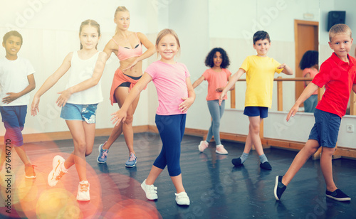 Fototapeta Naklejka Na Ścianę i Meble -  Group of tweens doing dance workout with female coach in classic choreography class..
