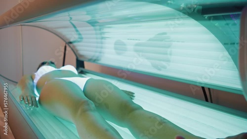 Video of beautiful woman having tanning skin treatment in a solarium photo