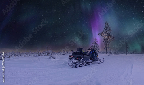 Scenic very frozen snowy young pine tree forest under Aurora skies, snowmobile and Northern Lights. Winter landscape In Northern Sweden, Vasterbotten, Umea.
