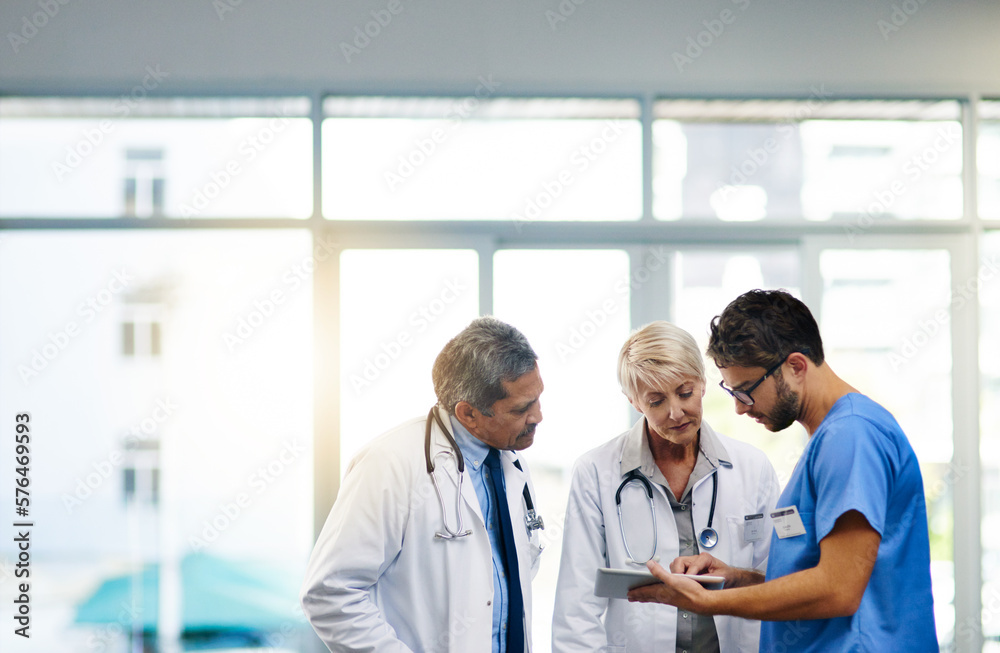 Fototapeta premium Smart doctors use smart apps. Shot of a team of doctors using a digital tablet together in a hospital.