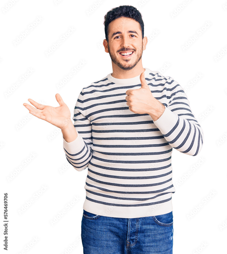 Young hispanic man wearing casual clothes showing palm hand and doing ok gesture with thumbs up, smiling happy and cheerful Young hispanic man wearing casual clothes showing palm hand and doing ok gesture with thumbs up, smiling happy and cheerful