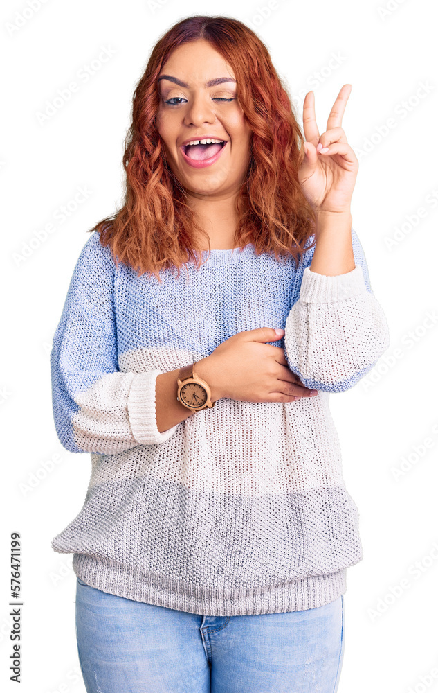 Obraz premium Young latin woman wearing casual clothes smiling with happy face winking at the camera doing victory sign with fingers. number two.