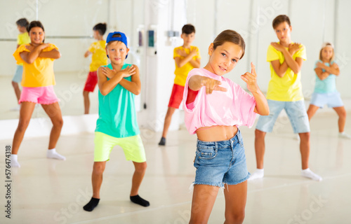 Portrait of preteen girl practicing hip-hop movements during group dance lesson in studio.