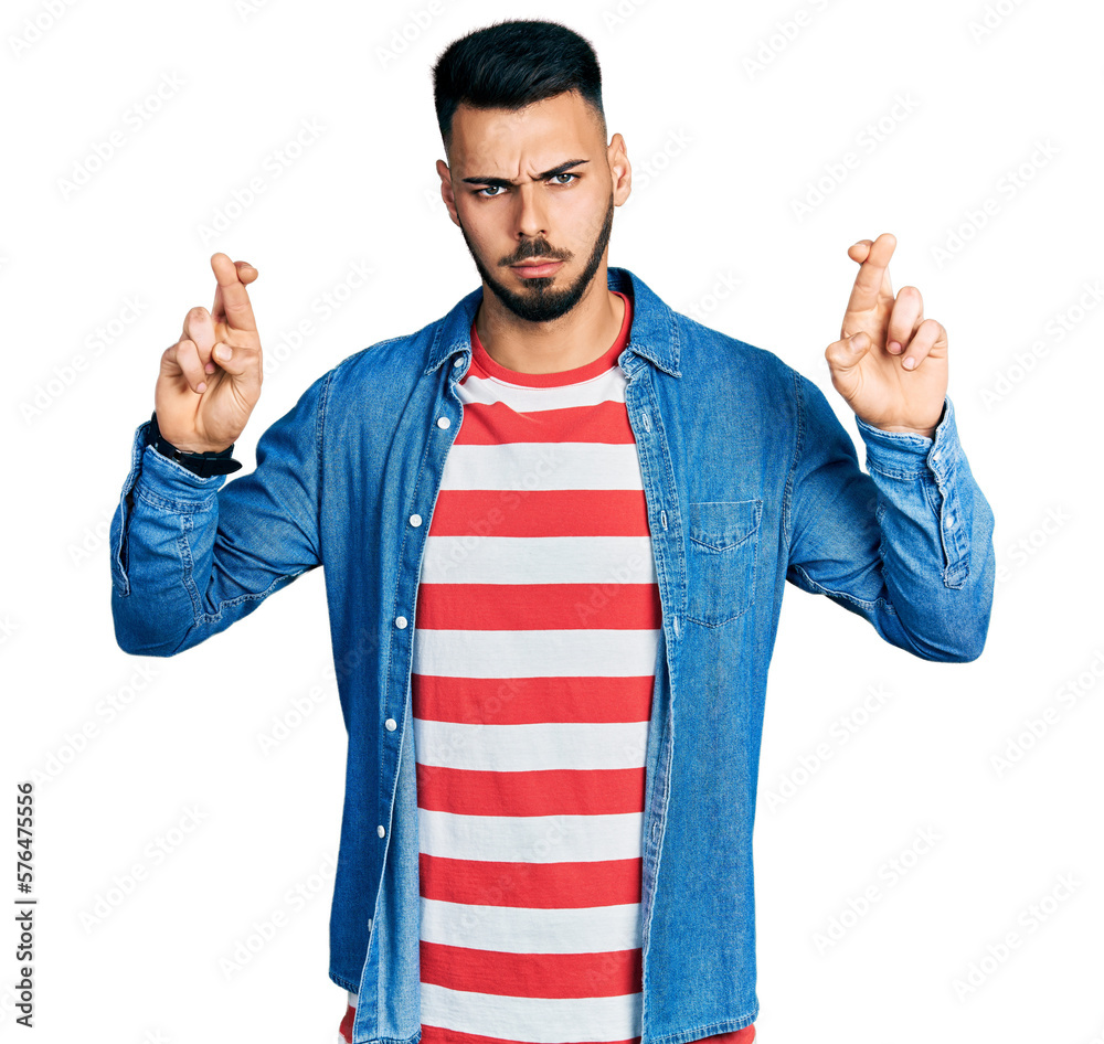 Young hispanic man with beard doing fingers crossed luck gesture skeptic and nervous, frowning upset because of problem. negative person. Young hispanic man with beard doing fingers crossed luck gesture skeptic and nervous, frowning upset because of problem. negative person.