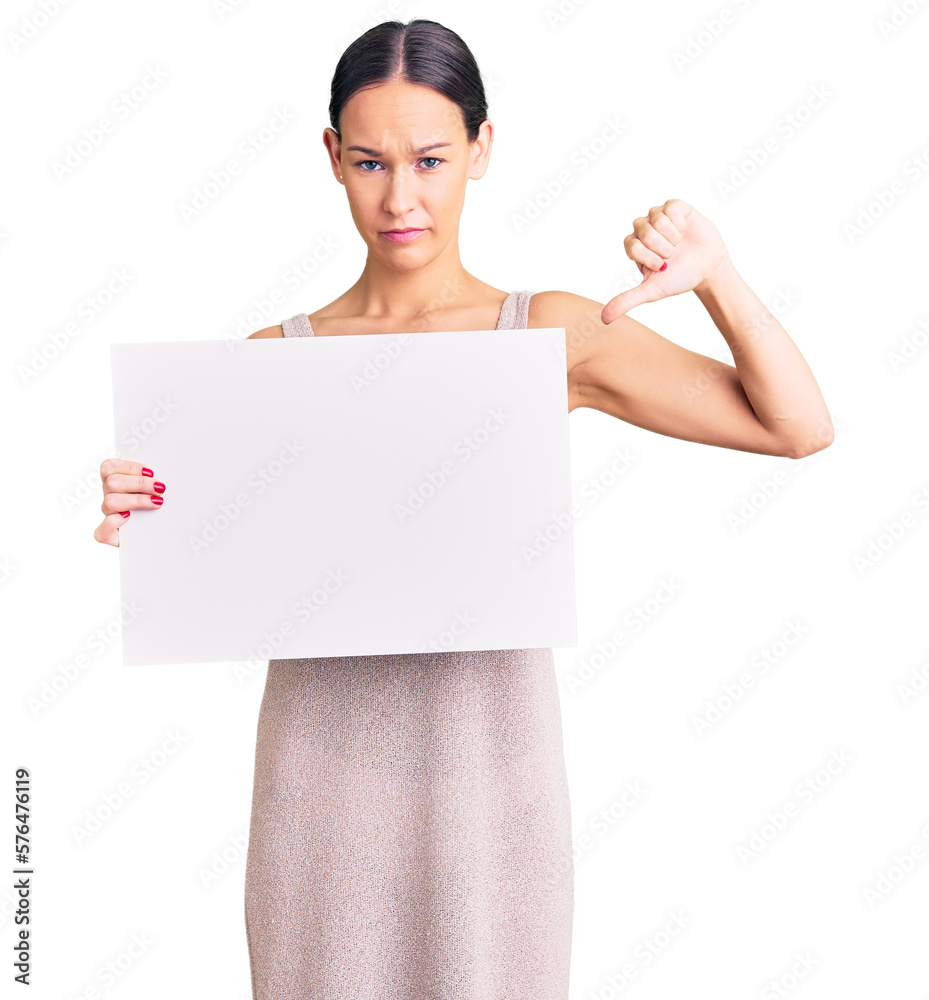 Beautiful brunette young woman holding blank empty banner with angry face, negative sign showing dislike with thumbs down, rejection concept Beautiful brunette young woman holding blank empty banner with angry face, negative sign showing dislike with thumbs down, rejection concept