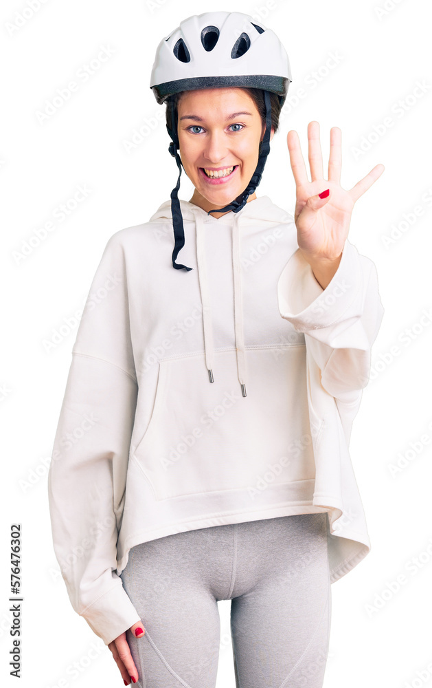 Beautiful brunette young woman wearing bike helmet and sporty clothes showing and pointing up with fingers number four while smiling confident and happy. Beautiful brunette young woman wearing bike helmet and sporty clothes showing and pointing up with fingers number four while smiling confident and happy.
