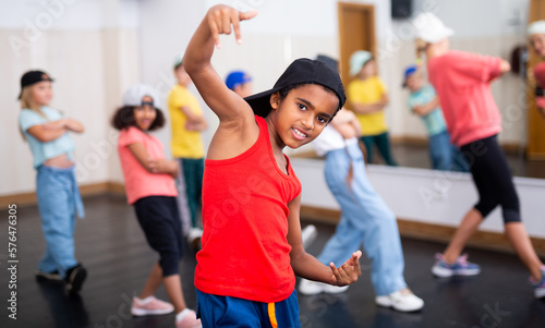 Portrait of emotional african boy doing hip hop movements during group class in dance center