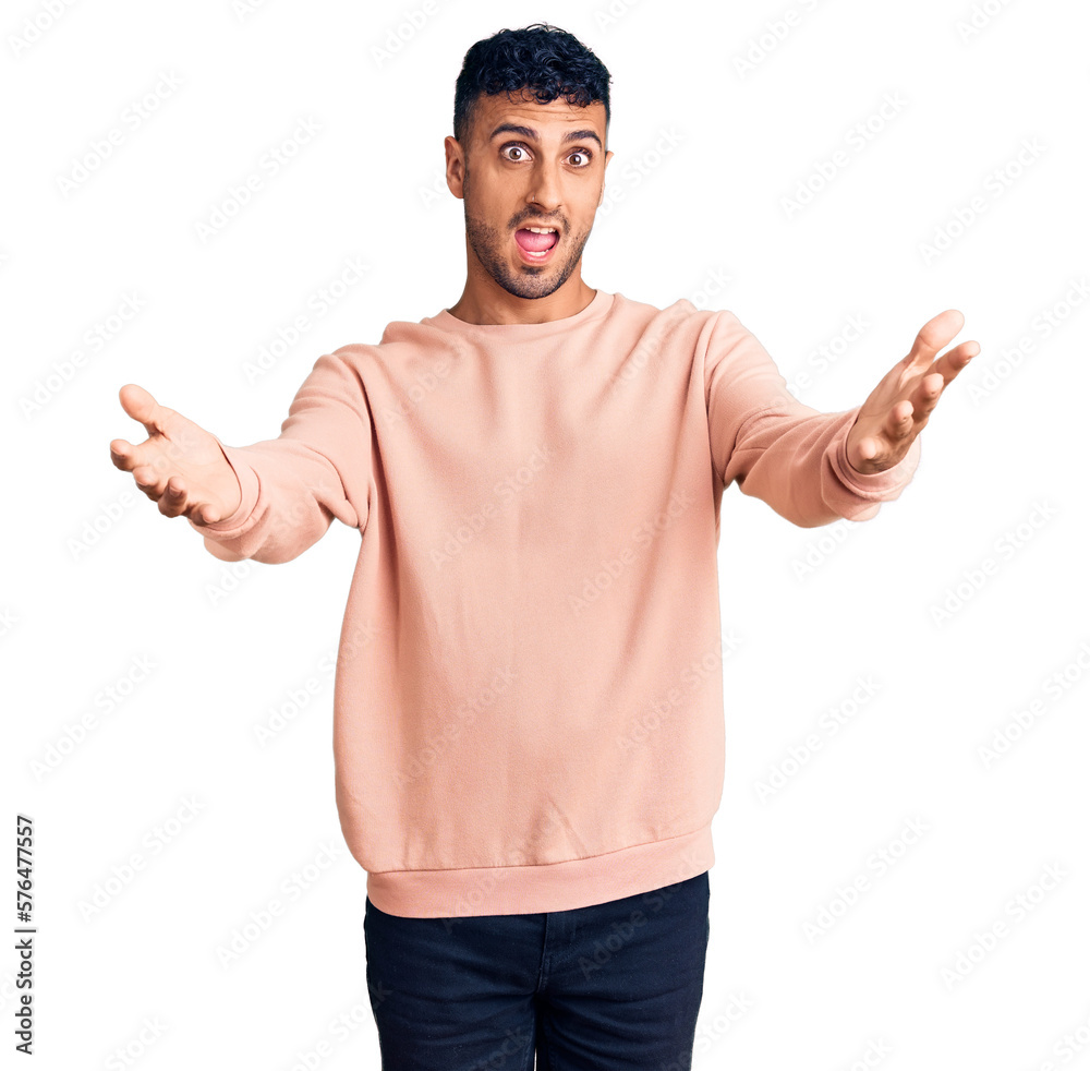 Young hispanic man wearing casual clothes smiling cheerful offering hands giving assistance and acceptance. Young hispanic man wearing casual clothes smiling cheerful offering hands giving assistance and acceptance.