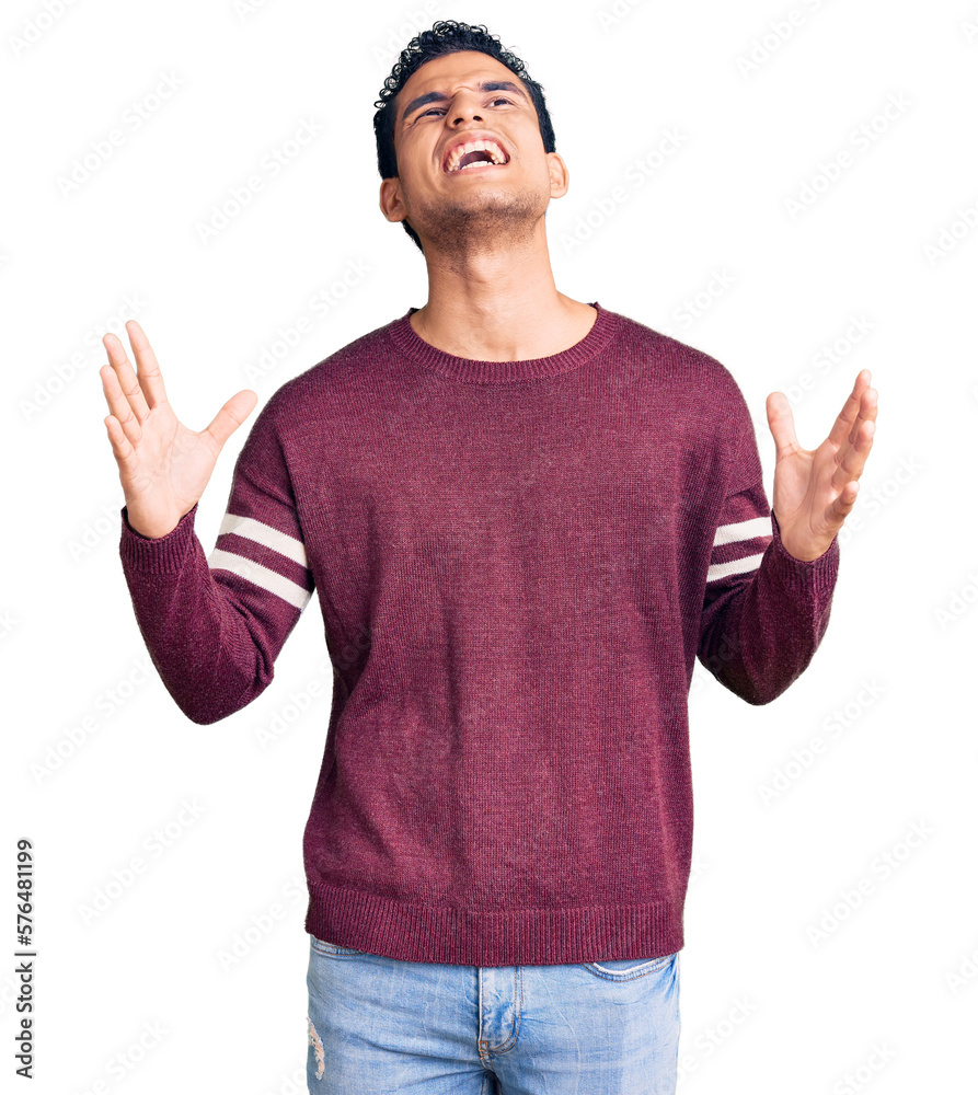 Naklejka premium Hispanic handsome young man wearing casual clothes crazy and mad shouting and yelling with aggressive expression and arms raised. frustration concept.
