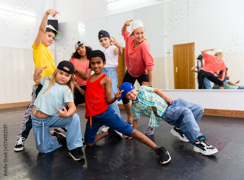Fototapeta Naklejka Na Ścianę i Meble -  Portrait of cheerful preteen girl practicing dance movements with group of children in choreography class