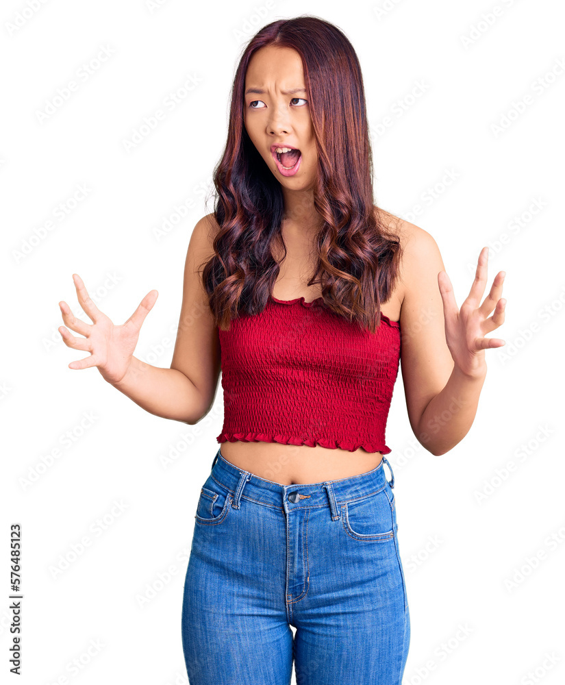 Young beautiful chinese girl wearing casual clothes crazy and mad shouting and yelling with aggressive expression and arms raised. frustration concept. Young beautiful chinese girl wearing casual clothes crazy and mad shouting and yelling with aggressive expression and arms raised. frustration concept.