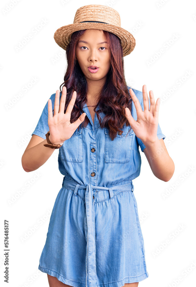 Young beautiful chinese girl wearing summer hat moving away hands palms showing refusal and denial with afraid and disgusting expression. stop and forbidden. Young beautiful chinese girl wearing summer hat moving away hands palms showing refusal and denial with afraid and disgusting expression. stop and forbidden.