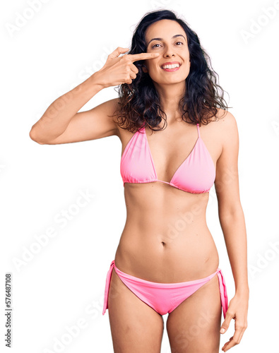 Young beautiful hispanic woman wearing bikini pointing with hand finger to face and nose, smiling cheerful. beauty concept © Krakenimages.com