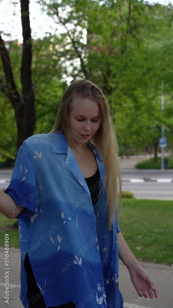 Close-up view of cute beautiful blonde girl in a walking along the evening city center and fluffing her silky hair Close-up view of cute beautiful blonde girl in a walking along the evening city center and fluffing her silky hair