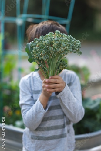 Young boy holding up broccoli 