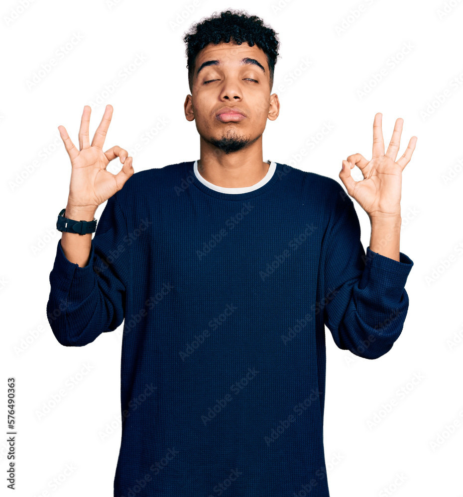 Young african american man wearing casual clothes relaxed and smiling with eyes closed doing meditation gesture with fingers. yoga concept. Young african american man wearing casual clothes relaxed and smiling with eyes closed doing meditation gesture with fingers. yoga concept.