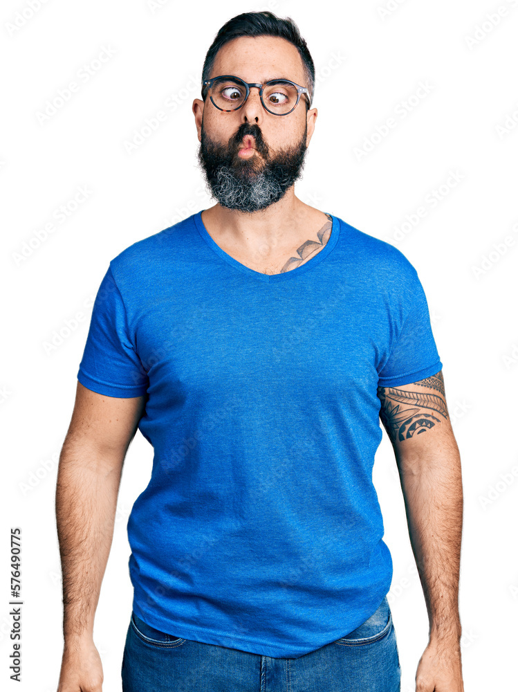 Hispanic man with beard wearing casual t shirt and glasses making fish face with lips, crazy and comical gesture. funny expression. Hispanic man with beard wearing casual t shirt and glasses making fish face with lips, crazy and comical gesture. funny expression.