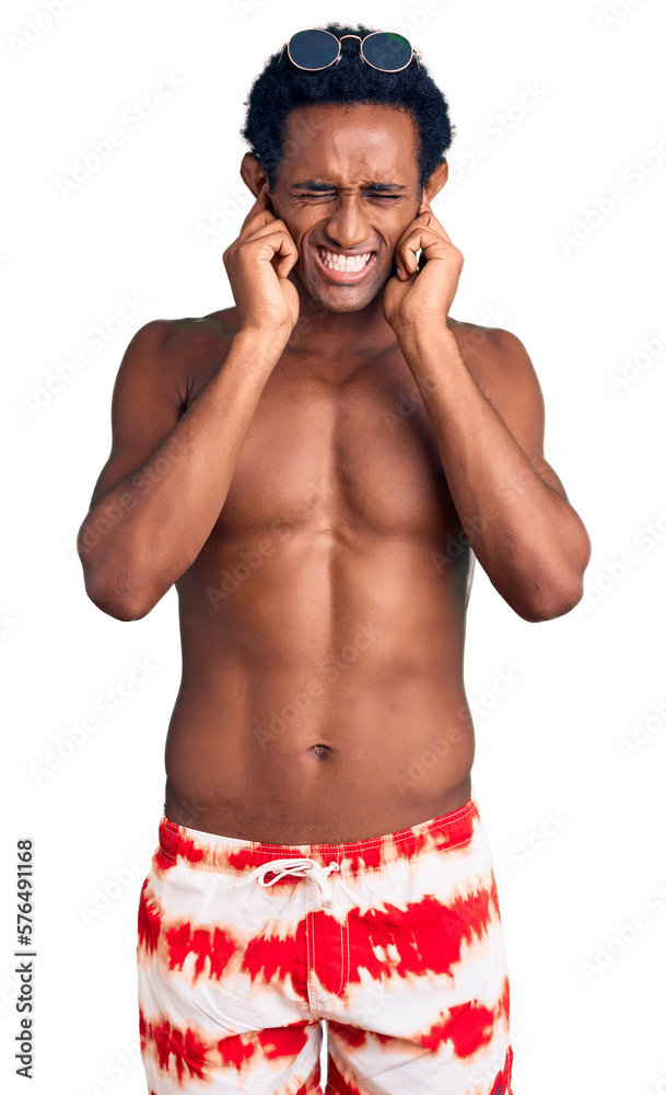 Fototapeta premium African handsome man wearing swimsuit and sunglasses covering ears with fingers with annoyed expression for the noise of loud music. deaf concept.