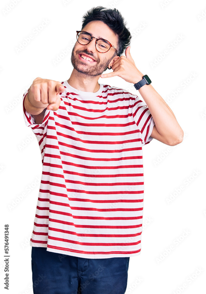 Fototapeta premium Young hispanic man wearing casual clothes smiling doing talking on the telephone gesture and pointing to you. call me.
