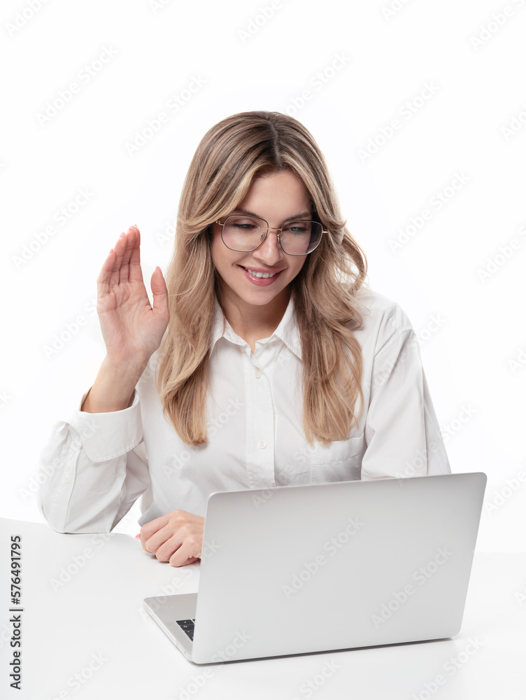Young smiling businesswoman wearing glasses sitting behind a desk and waving her hand to a webcam or laptop. Concept of businesswoman talking and waving online via video chat. Video conference
Young smiling businesswoman wearing glasses sitting behind a desk and waving her hand to a webcam or laptop. Concept of businesswoman talking and waving online via video chat. Video conference