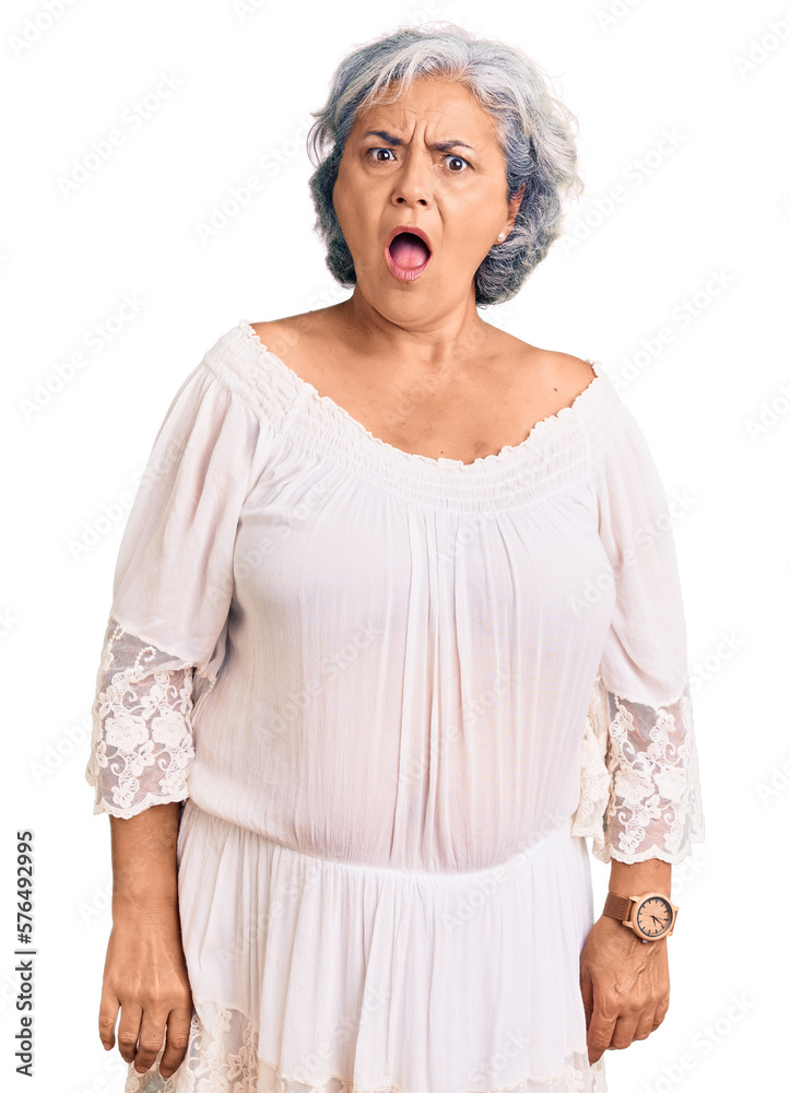 Senior woman with gray hair wearing bohemian style in shock face, looking skeptical and sarcastic, surprised with open mouth Senior woman with gray hair wearing bohemian style in shock face, looking skeptical and sarcastic, surprised with open mouth