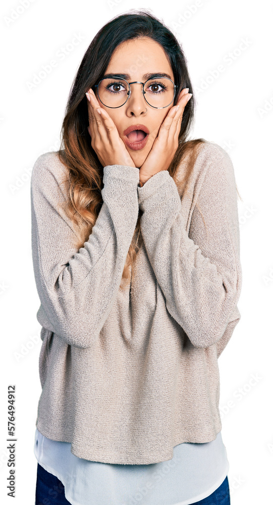 Beautiful hispanic woman wearing casual sweater and glasses afraid and shocked, surprise and amazed expression with hands on face Beautiful hispanic woman wearing casual sweater and glasses afraid and shocked, surprise and amazed expression with hands on face
