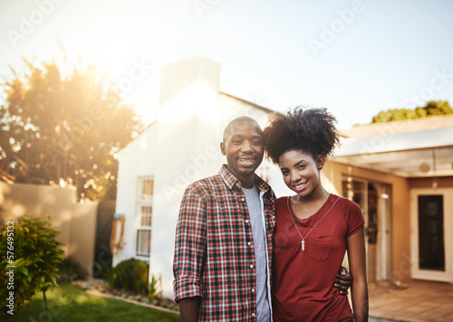 Proud first-time homeowners. Portrait of a young couple standing outside in front of their new house. © Delmaine D/peopleimages.com