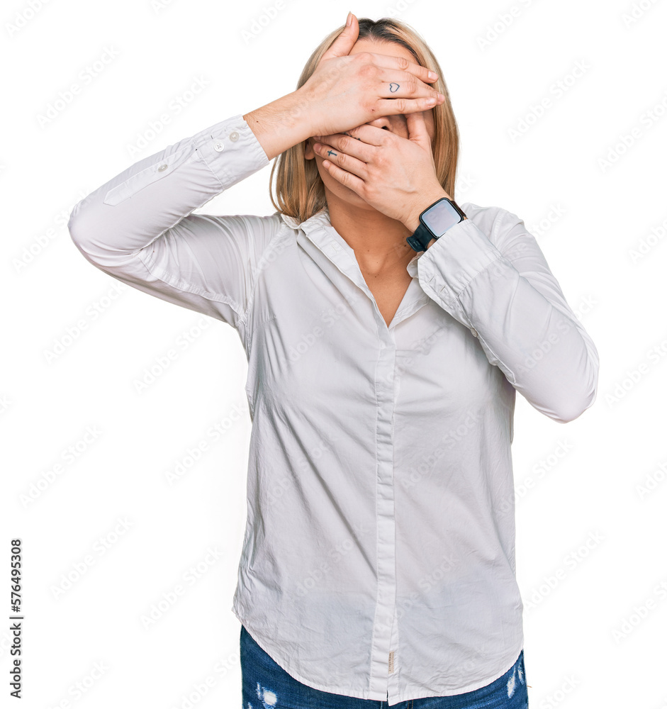 Young caucasian woman wearing casual clothes covering eyes and mouth with hands, surprised and shocked. hiding emotion Young caucasian woman wearing casual clothes covering eyes and mouth with hands, surprised and shocked. hiding emotion