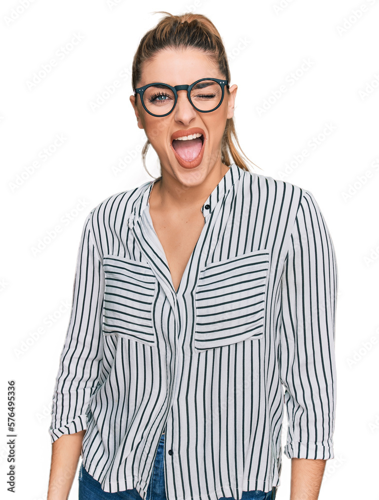 Young caucasian woman wearing business shirt and glasses winking looking at the camera with sexy expression, cheerful and happy face.