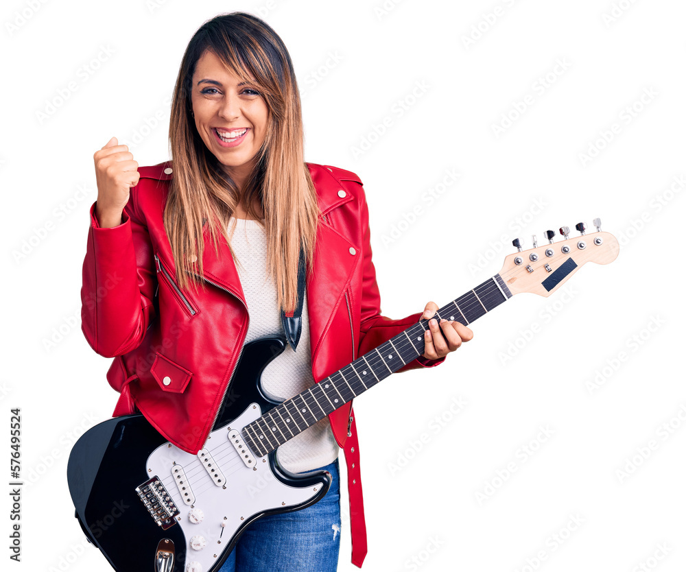 Young beautiful woman playing electric guitar screaming proud, celebrating victory and success very excited with raised arms
