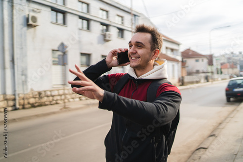 A young guy is going through the city while pushing his bicycle and using the phone during the day