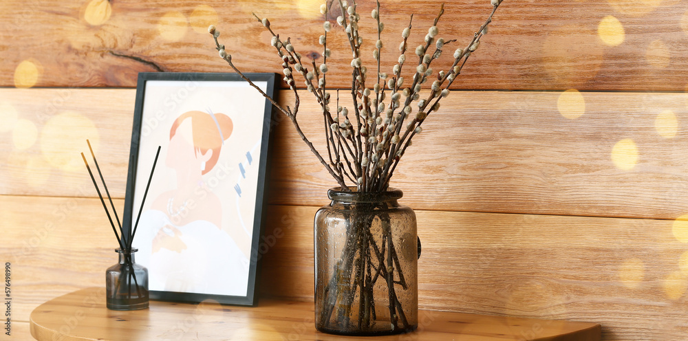 Vase with willow branches and picture near wooden wall in room Vase with willow branches and picture near wooden wall in room
