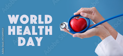 Hands of cardiologist with stethoscope and red heart on blue background. World Health Day photo
