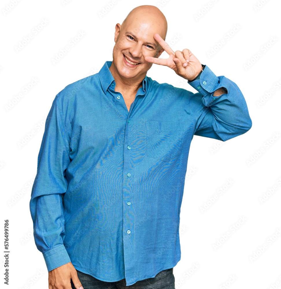 Middle age bald man wearing casual clothes doing peace symbol with fingers over face, smiling cheerful showing victory Middle age bald man wearing casual clothes doing peace symbol with fingers over face, smiling cheerful showing victory