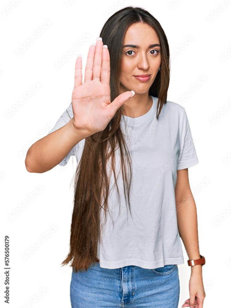 Young hispanic girl wearing casual white t shirt doing stop sing with palm of the hand. warning expression with negative and serious gesture on the face. Young hispanic girl wearing casual white t shirt doing stop sing with palm of the hand. warning expression with negative and serious gesture on the face.
