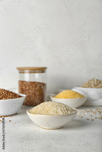 Bowl with rice and different cereals on light background