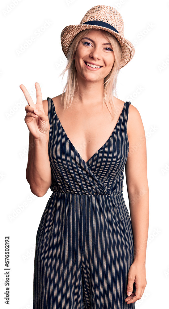 Young beautiful blonde woman wearing summer hat and dress showing and pointing up with fingers number two while smiling confident and happy. Young beautiful blonde woman wearing summer hat and dress showing and pointing up with fingers number two while smiling confident and happy.
