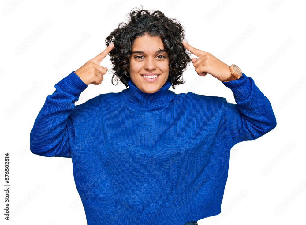 Young hispanic woman with curly hair wearing turtleneck sweater smiling pointing to head with both hands finger, great idea or thought, good memory Young hispanic woman with curly hair wearing turtleneck sweater smiling pointing to head with both hands finger, great idea or thought, good memory