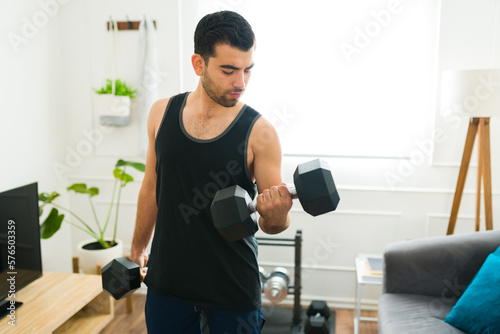 Strong young man using weights during his home workout