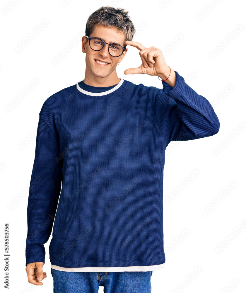 Young handsome man wearing casual clothes and glasses smiling and confident gesturing with hand doing small size sign with fingers looking and the camera. measure concept. Young handsome man wearing casual clothes and glasses smiling and confident gesturing with hand doing small size sign with fingers looking and the camera. measure concept.