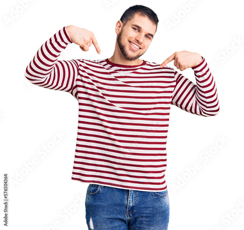 Young handsome man wearing striped sweater looking confident with smile on face, pointing oneself with fingers proud and happy.