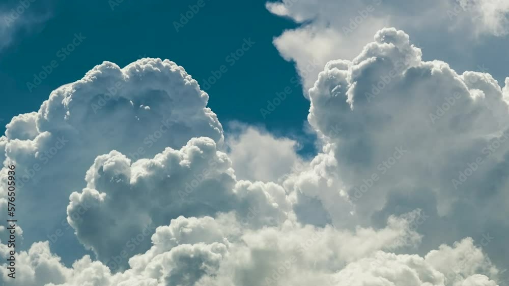 Timelapse of white puffy cumulus clouds forming on summer blue sky. Moving and changing cloudscape weather