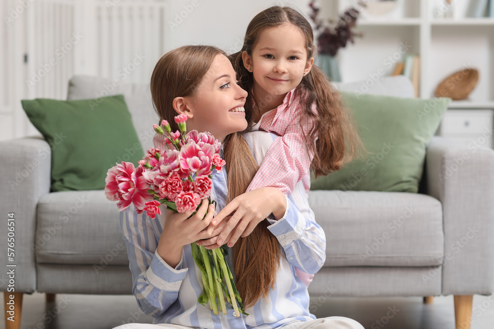 Cute little girl hugging her mother with flowers at home on holiday Cute little girl hugging her mother with flowers at home on holiday