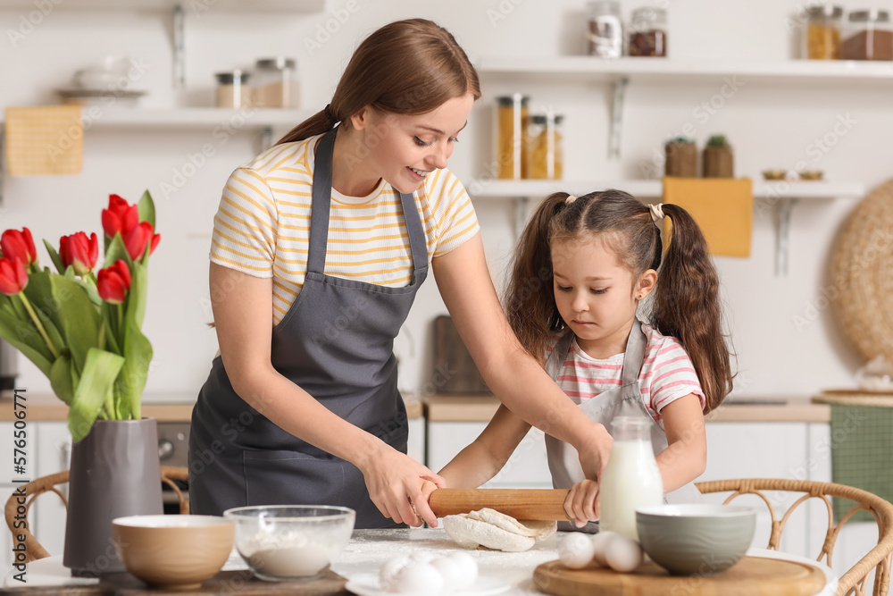 Little girl with her mom rolling out dough in kitchen on Mother's Day Little girl with her mom rolling out dough in kitchen on Mother's Day