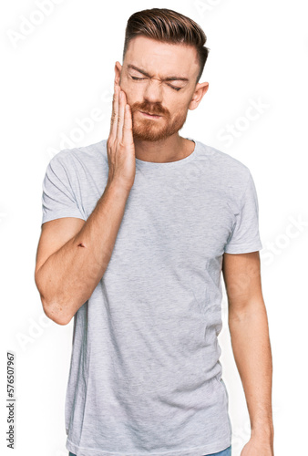 Young redhead man wearing casual grey t shirt touching mouth with hand with painful expression because of toothache or dental illness on teeth. dentist