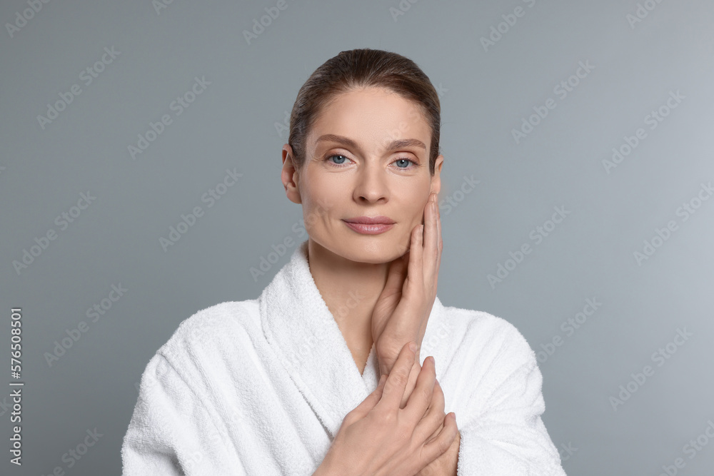 Woman massaging her face on grey background Woman massaging her face on grey background