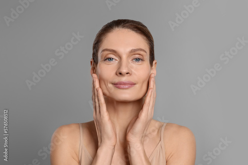 Tableau sur toile Woman massaging her face on grey background