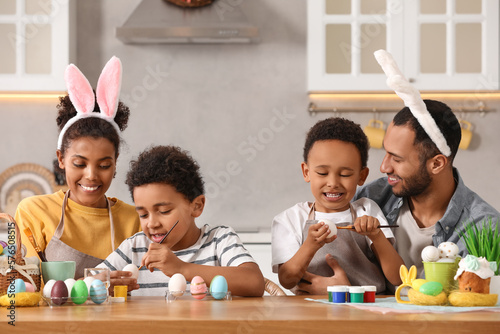 Fototapeta Happy African American family painting Easter eggs at table in kitchen