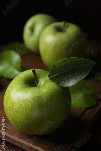 Fresh ripe green apples with leaves on wooden table, closeup